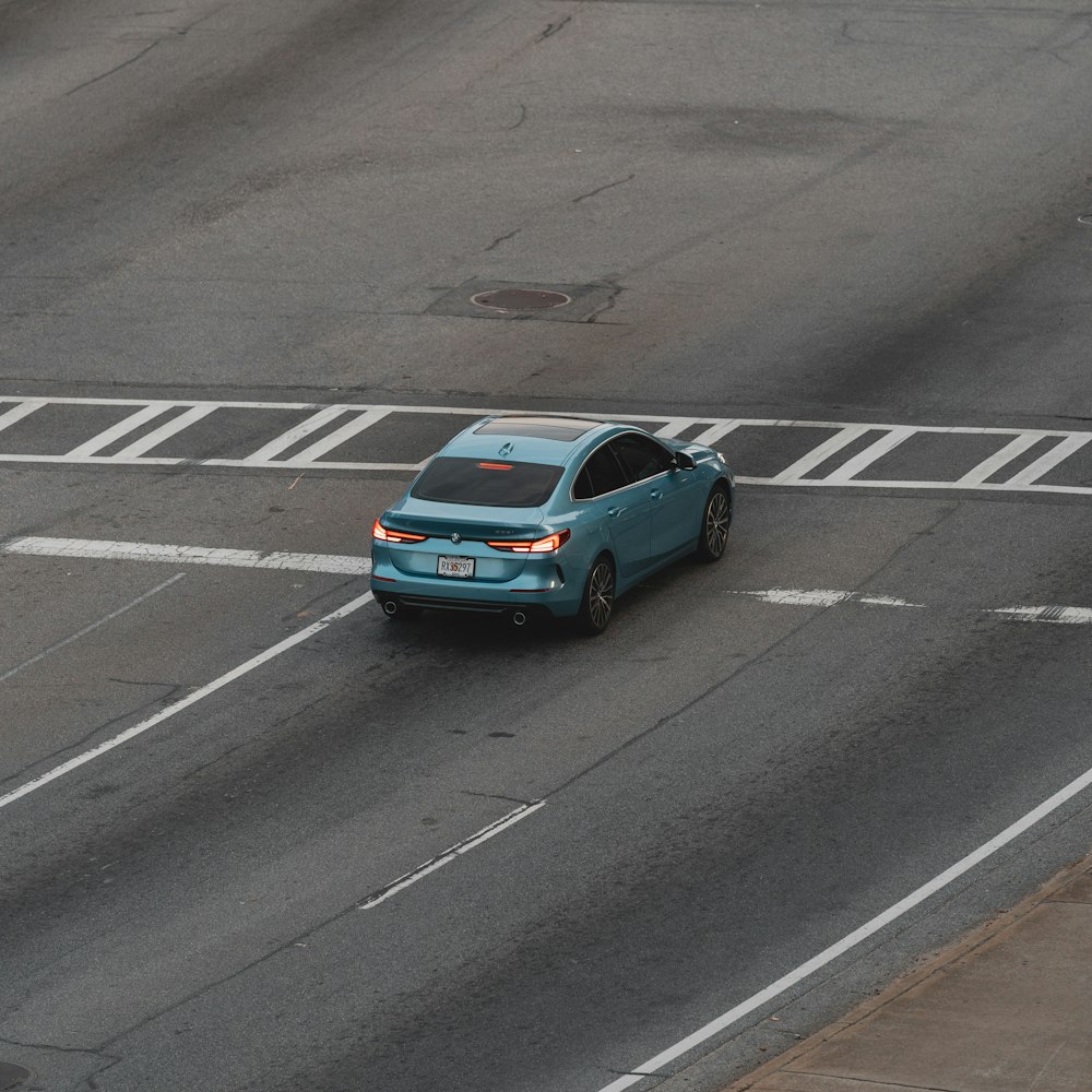 berline bleue sur route asphaltée grise pendant la journée