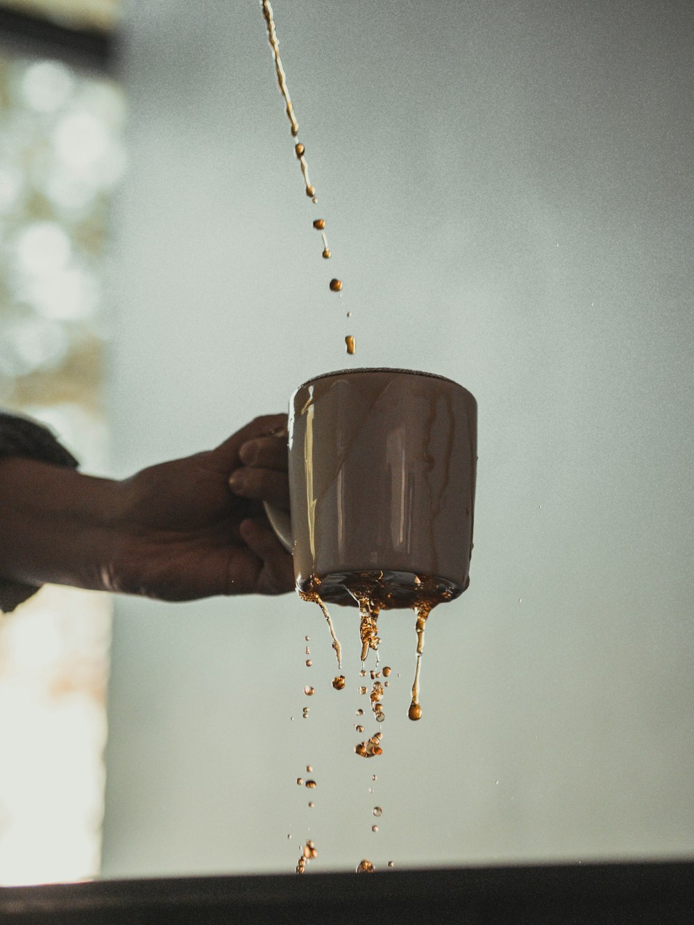 person pouring water on clear glass mug