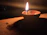 A softly glowing nilavilakku lamp casting warm light over intricate temple carvings.
