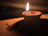 A softly glowing nilavilakku lamp casting warm light over intricate temple carvings.