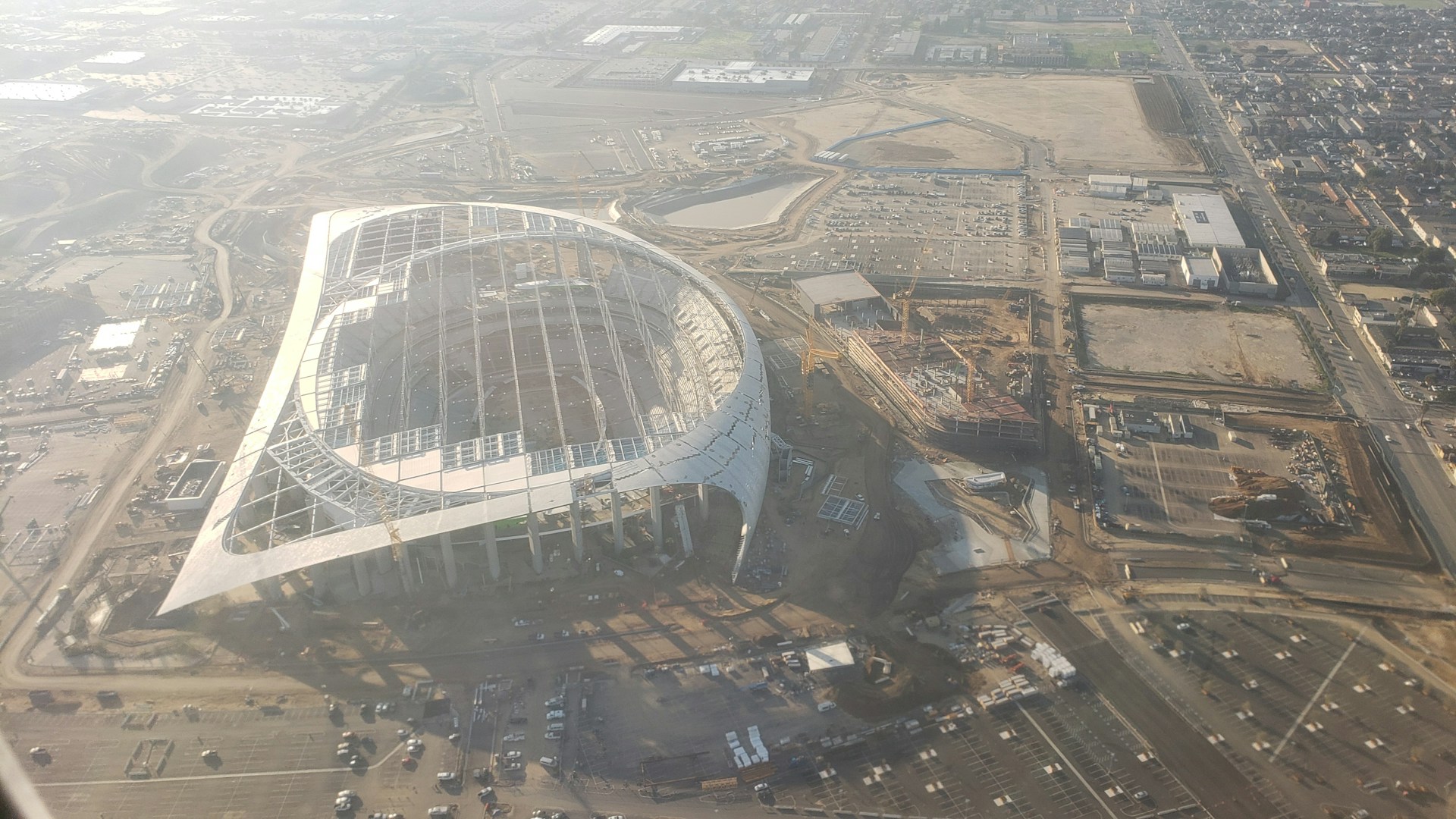 Construction workers and machinery actively remodeling the stadium, with scaffolding and new structures taking shape.