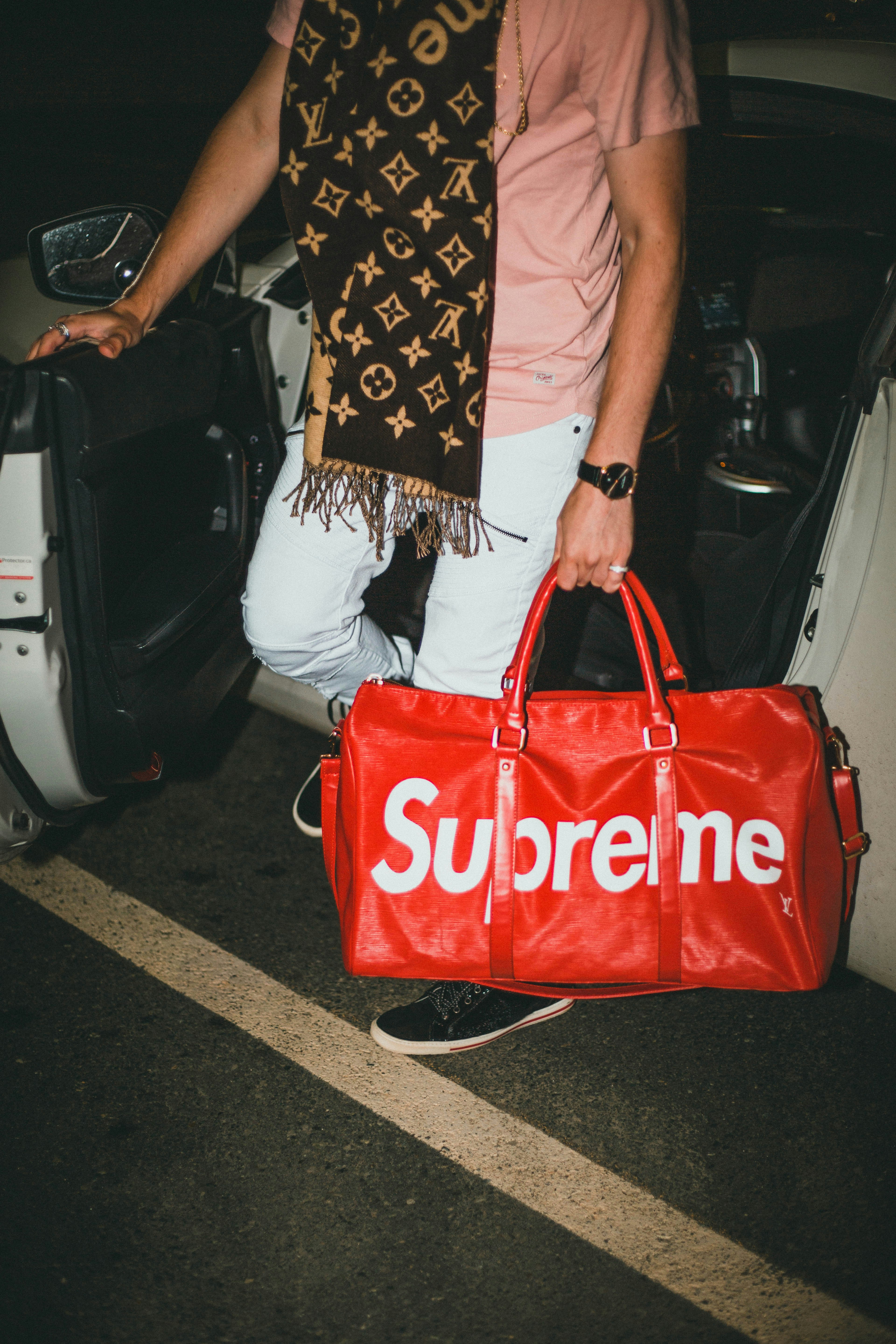 woman in white shirt holding orange and black tote bag