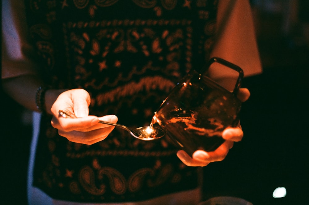 person holding clear glass mug with black liquid