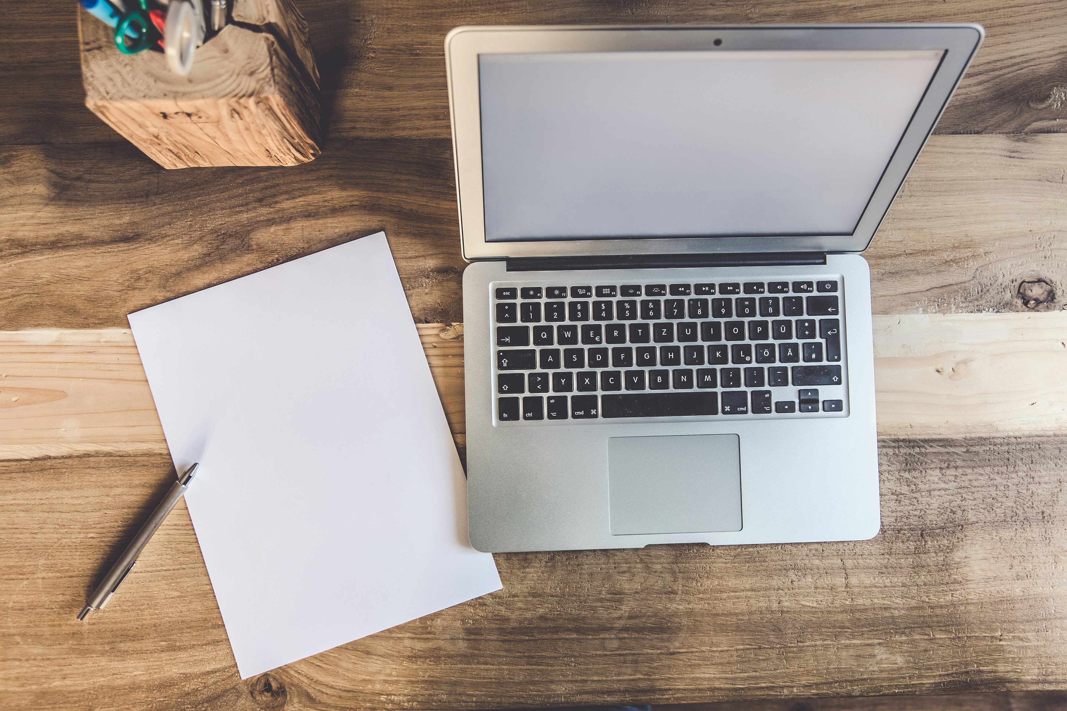 modern laptop on wooden desk alongside tablet and stylus