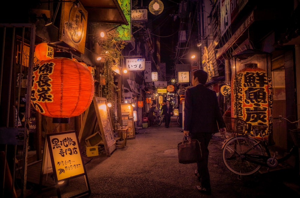 man in black jacket standing beside brown lantern during nighttime