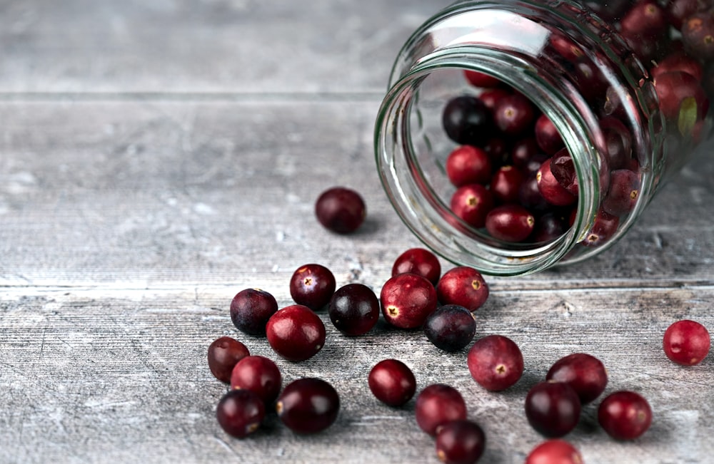 red round fruits in clear glass jar