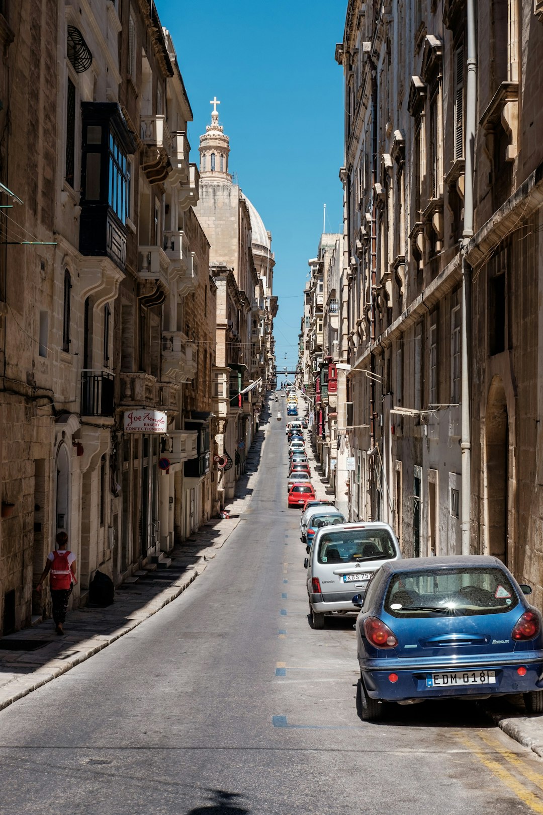 cars parked on the side of the road in between buildings