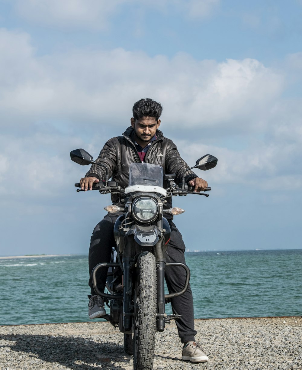 man in black jacket riding motorcycle on beach during daytime