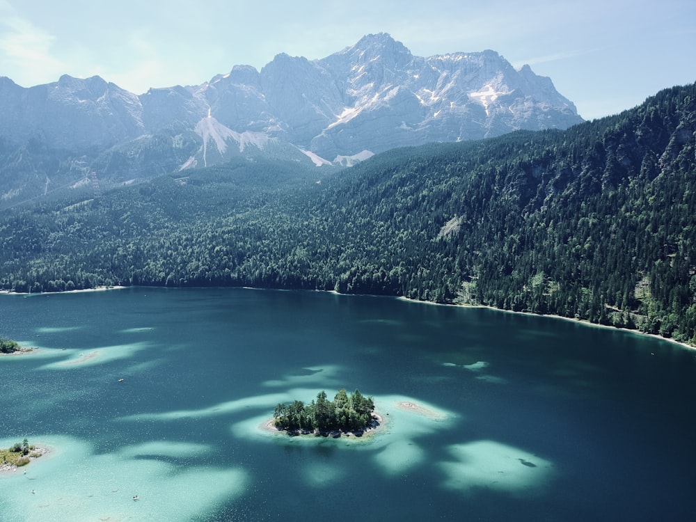 Lago verde circondato da alberi verdi e montagne durante il giorno