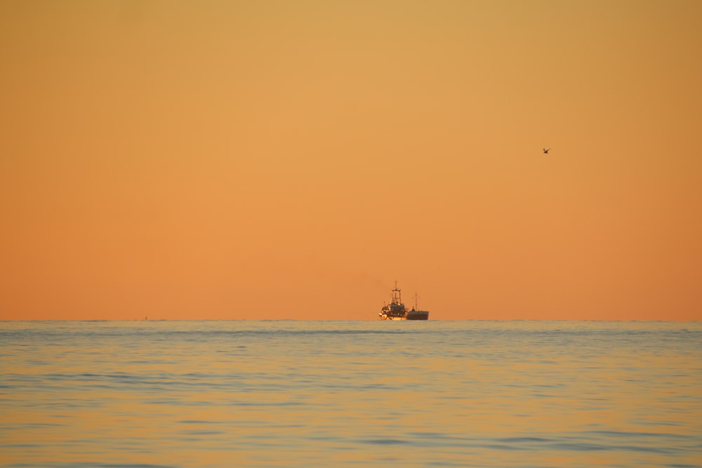 silhouette of ship on sea during sunset