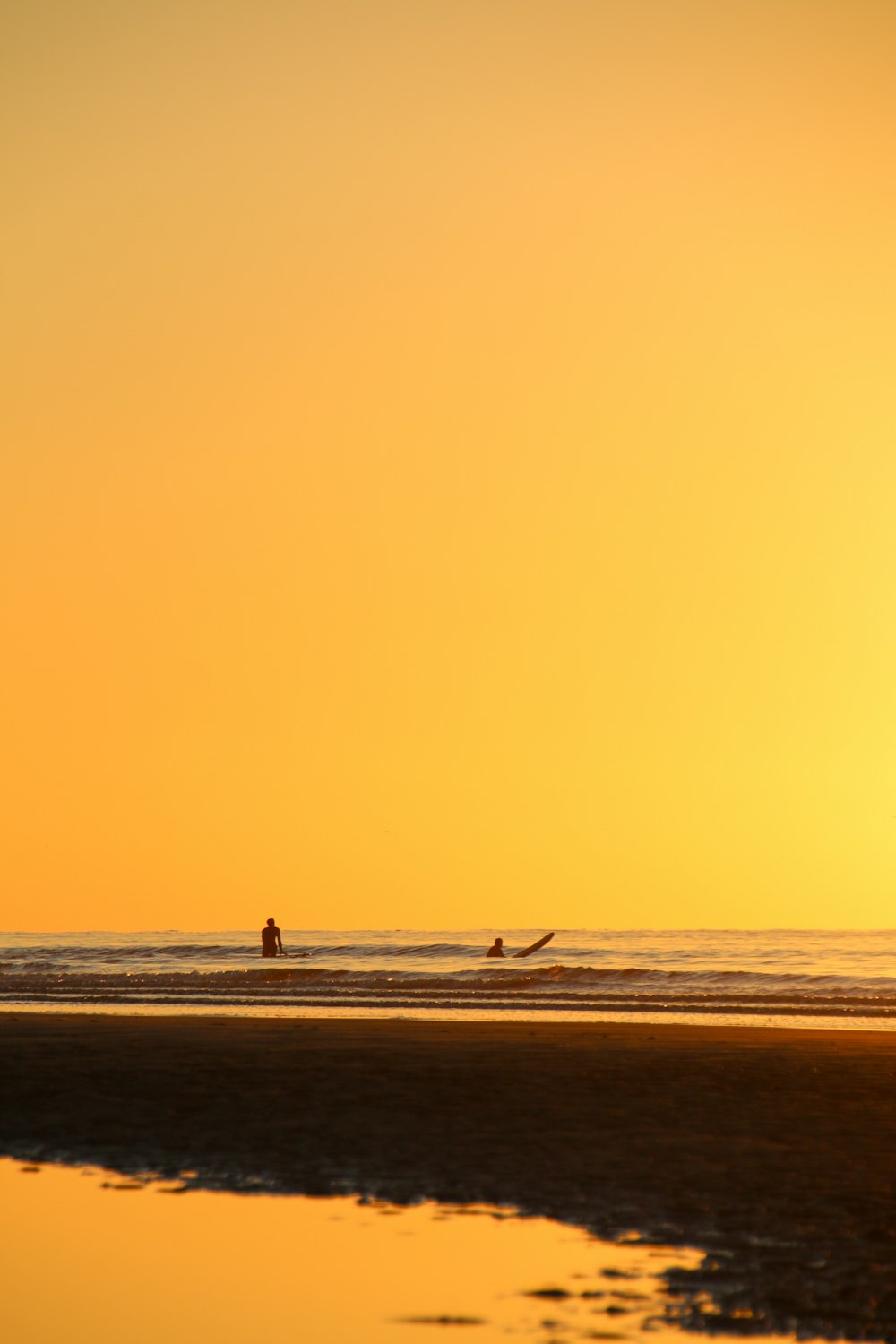 Silueta de persona caminando en la playa durante la puesta del sol