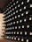 A neatly organized wine cellar with rows of wine bottles stored horizontally on wooden shelves. Each bottle is uniformly placed with corks facing outward, creating a visually appealing pattern. The cellar's ambient lighting casts a warm glow over the scene.