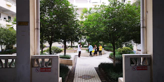 A group of neighbors sharing a friendly conversation in a sunny courtyard surrounded by well-kept homes.