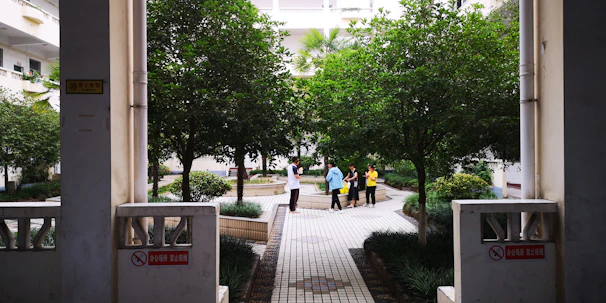A group of neighbors sharing a friendly conversation in a sunny courtyard surrounded by well-kept homes.