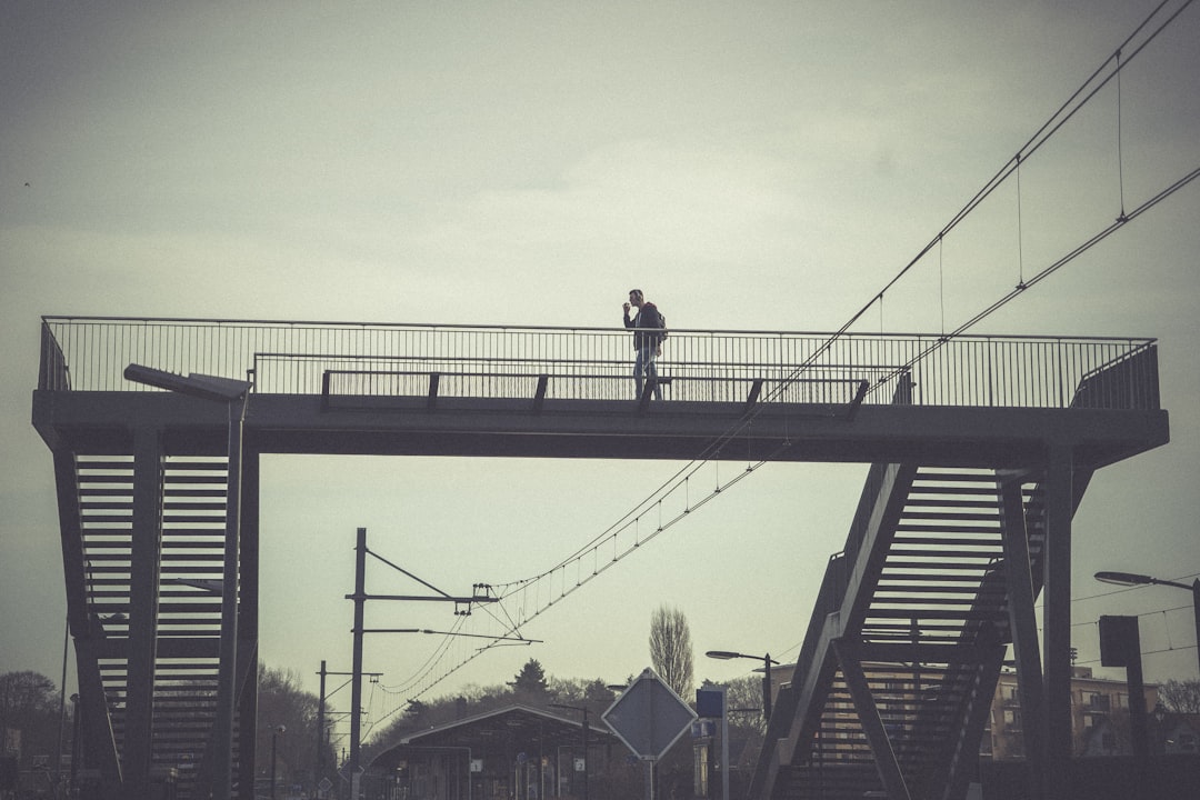 man in black jacket standing on black metal bridge during daytime