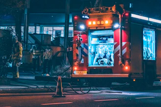 Emergency response team arriving at a residential fire site at night with equipment.