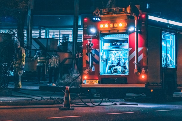A firefighter inspecting a fully equipped emergency vehicle at sunset.
