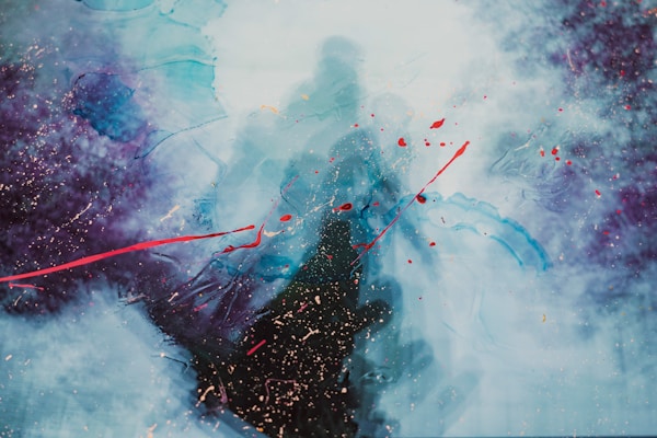 A vibrant abstract painting with swirling patterns of blue and purple, accented by bold red splashes across the canvas. The colors blend together to create a sense of movement and depth, with textured speckles that add a cosmic or dreamy quality.