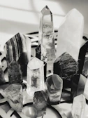 A collection of colorful crystals arranged on a wooden table with sunlight casting shadows.