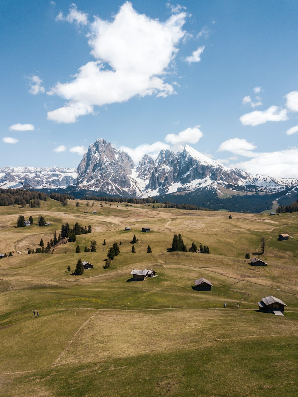 green grass field near mountain under blue sky during daytime