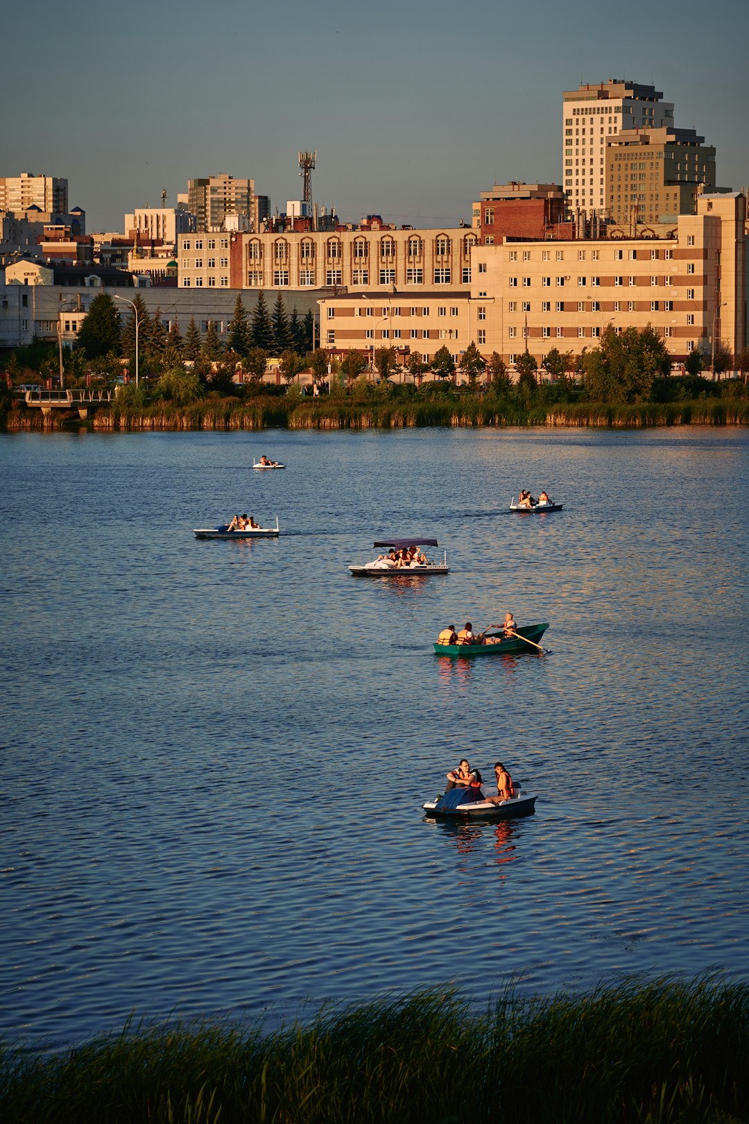 people riding on red boat on water near buildings during daytime