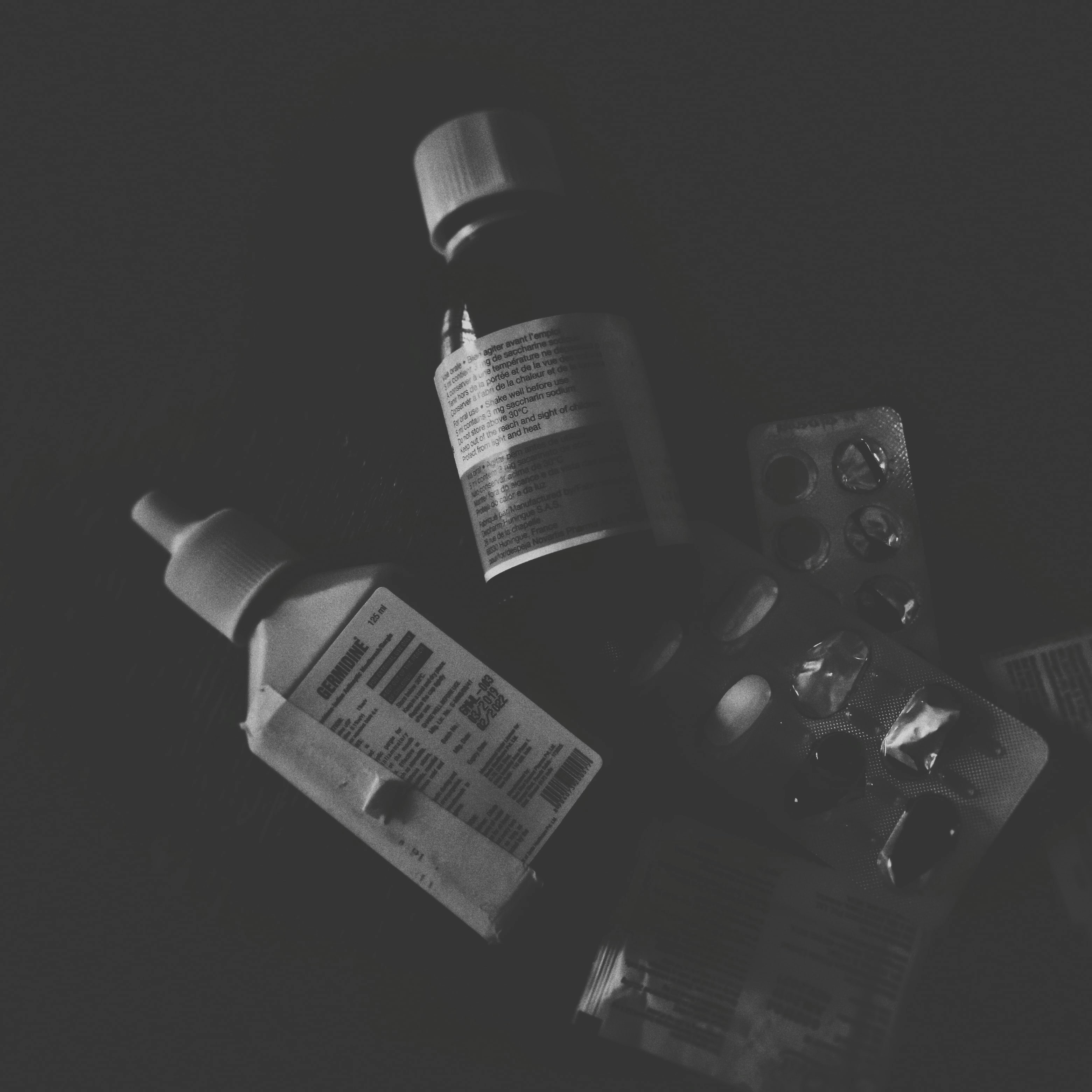 Medication and healthcare items on dark surface, moody low-key lighting