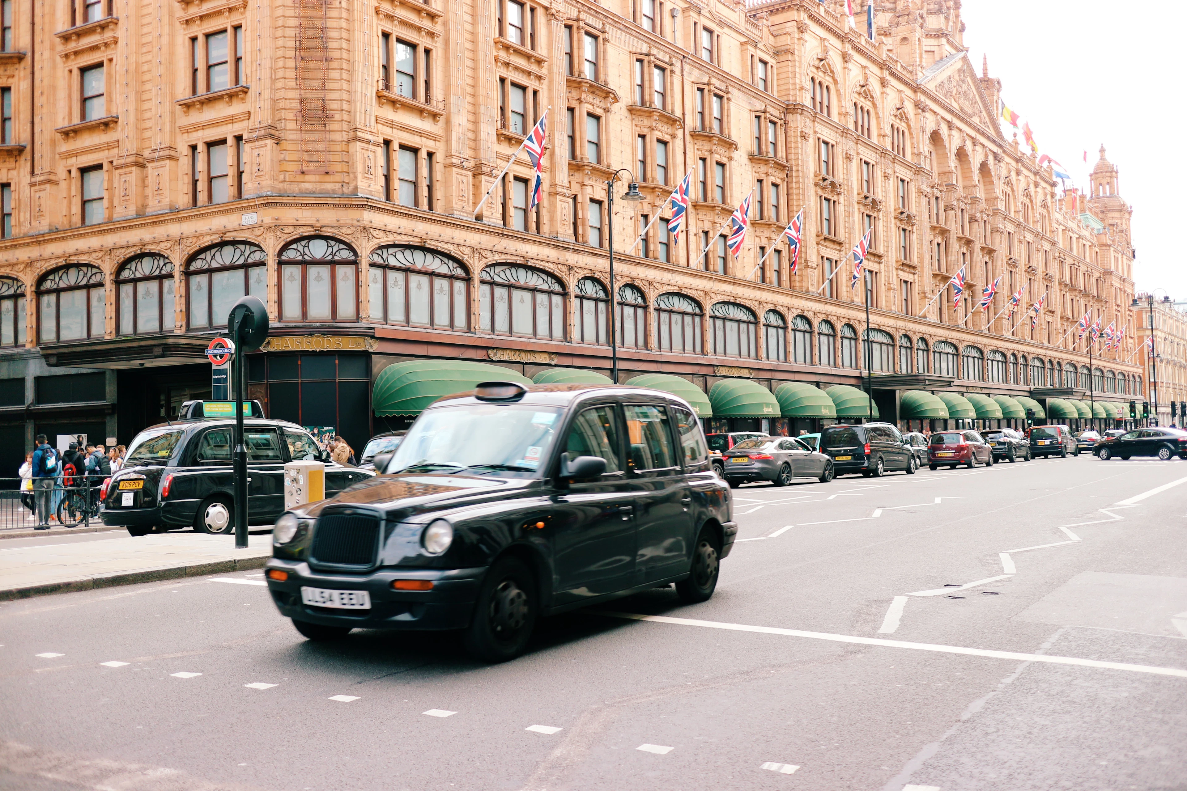 A black cab passing the terracotta facade of Harrods in Knightsbridge