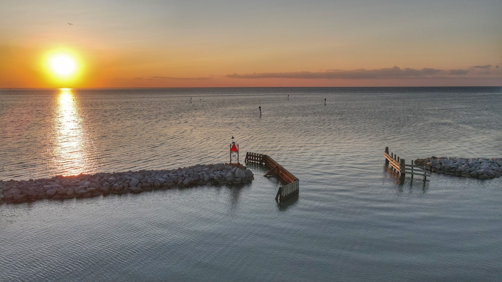 person in black shirt standing on brown wooden dock during sunset