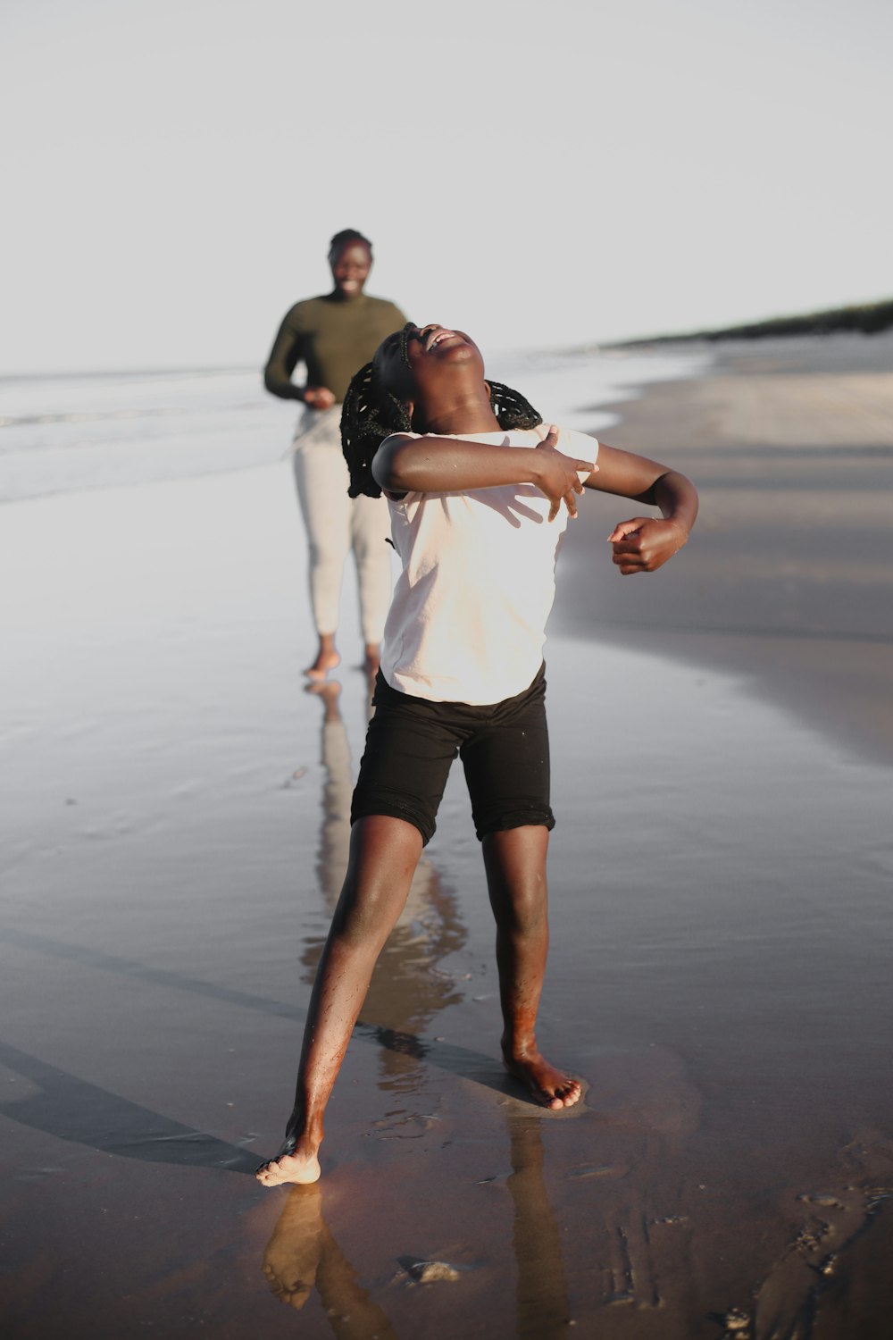 man in white shirt and black shorts running on beach during daytime