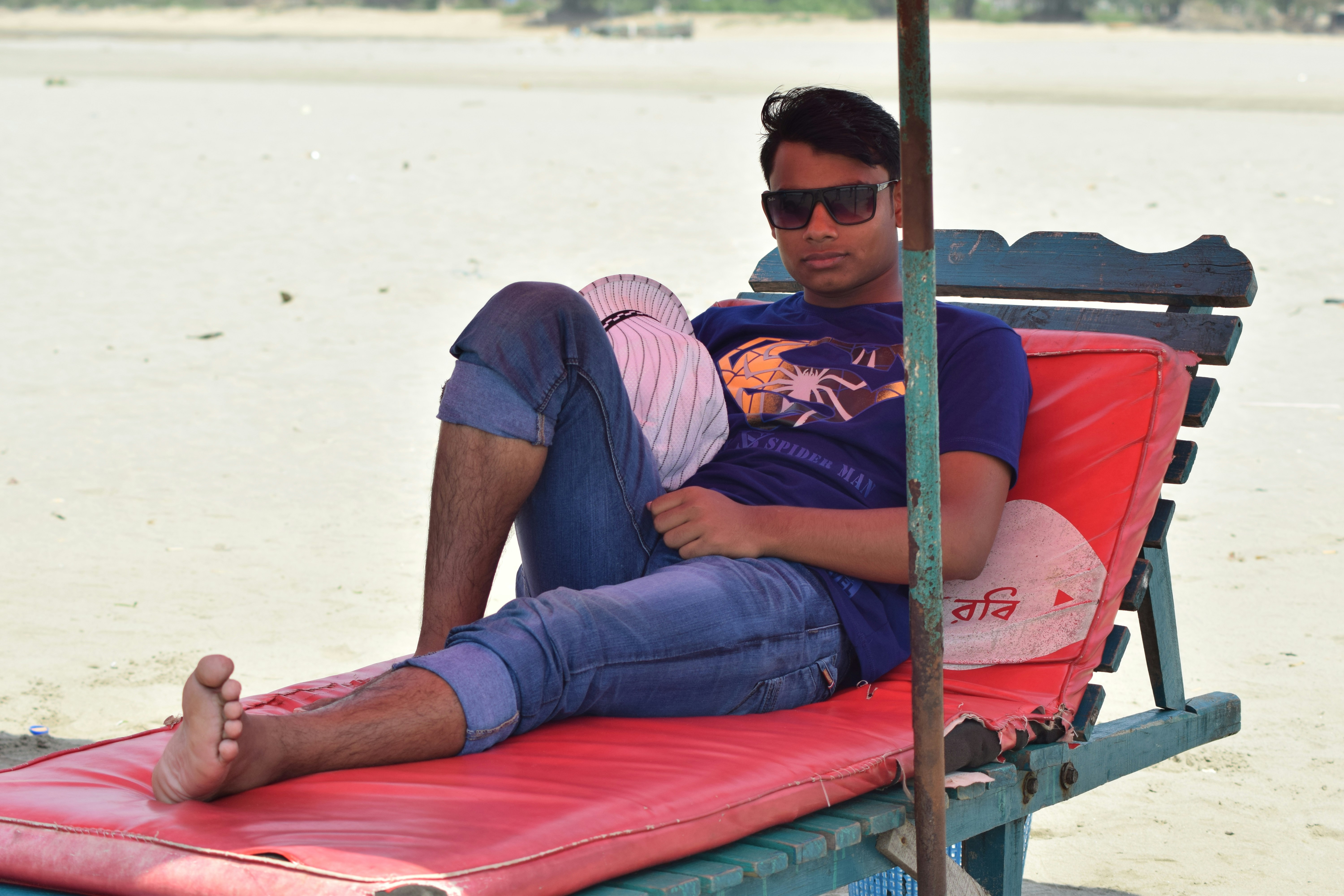 man in blue and white striped polo shirt and blue denim jeans sitting on red and