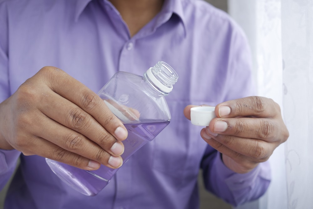 Persona sosteniendo una botella de plástico blanca