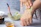 Close-up of hands applying herbal hair pack with fresh green leaves nearby