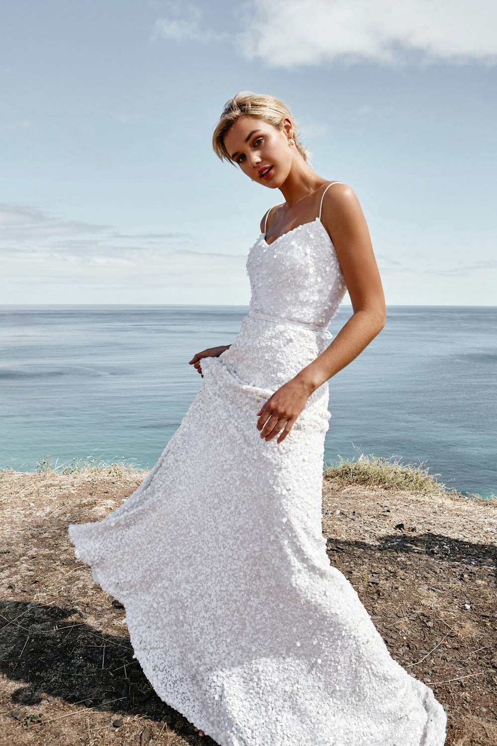 woman in white dress standing on beach during daytime