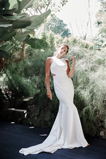 An elegant outfit featuring a flowing cream dress with subtle pleats, captured outdoors in soft natural light.