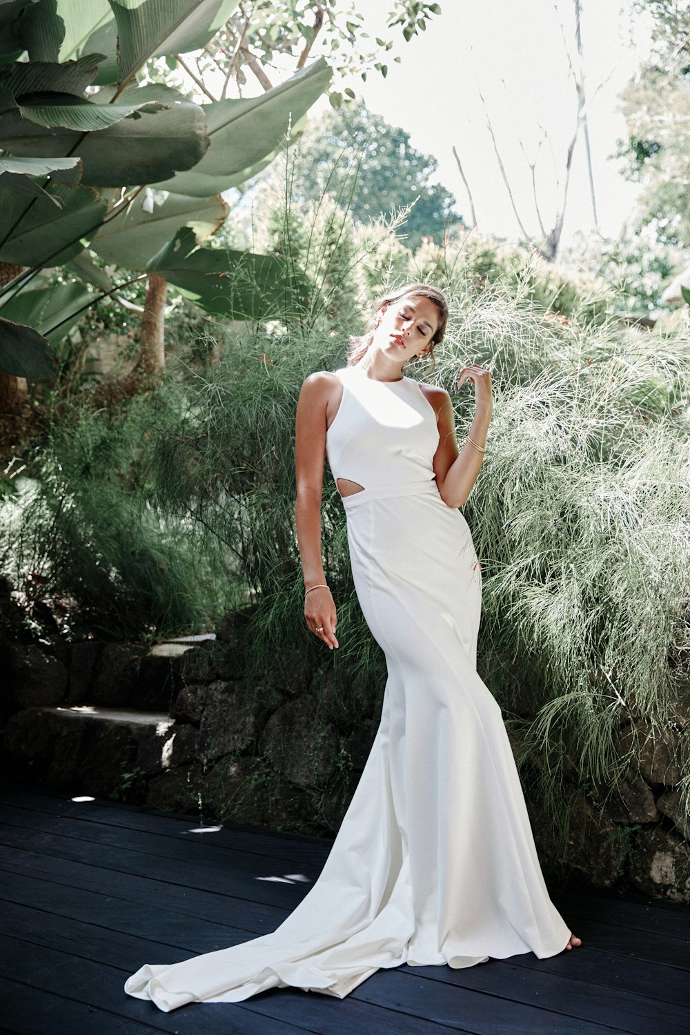 woman in white sleeveless dress standing beside green plants during daytime