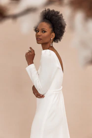 A model wearing a sleek, shiny human hair wig with a cream white and soft gold backdrop.