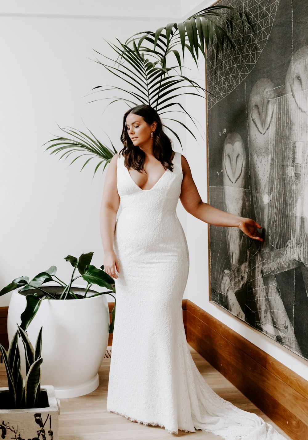 woman in white sleeveless dress standing beside green plant