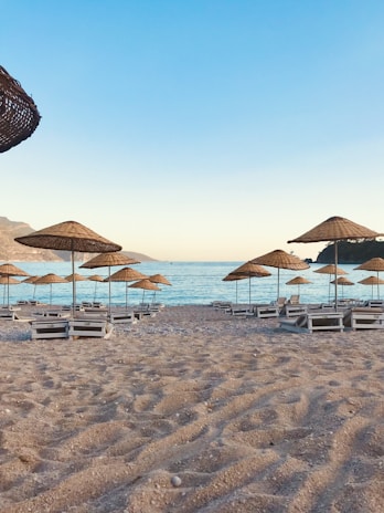 A serene beach setting with elegant lounge chairs and umbrellas.