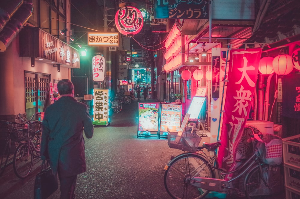 man in black jacket walking on sidewalk during nighttime