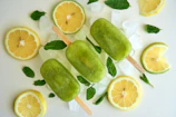 A refreshing lime popsicle with droplets of condensation on a bright blue plate.