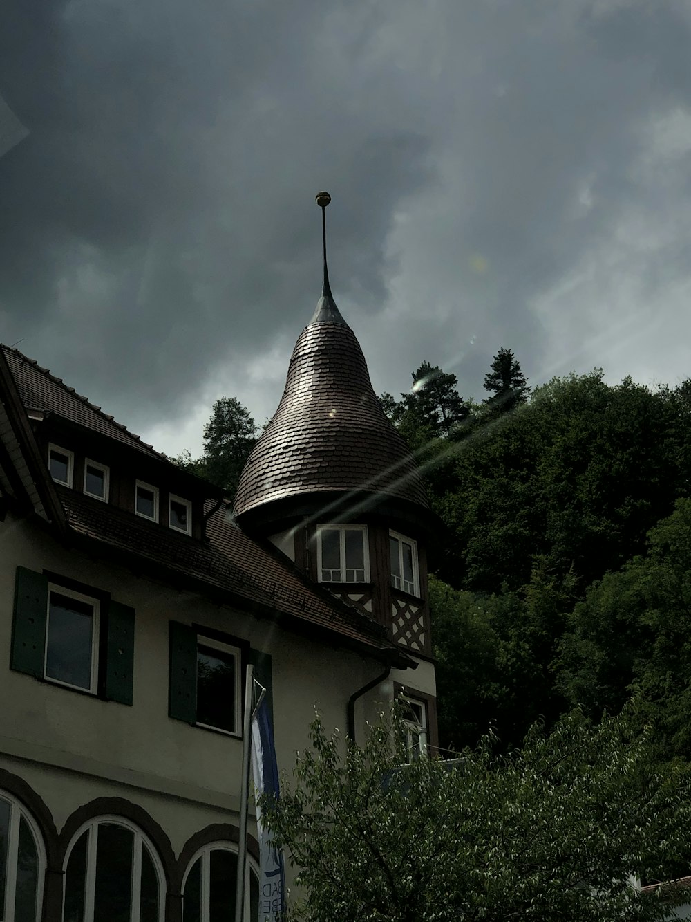 brown and white house near green trees under white clouds and blue sky during daytime