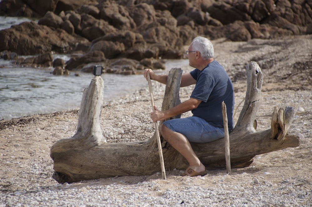 man in blue polo shirt sitting on brown wooden log