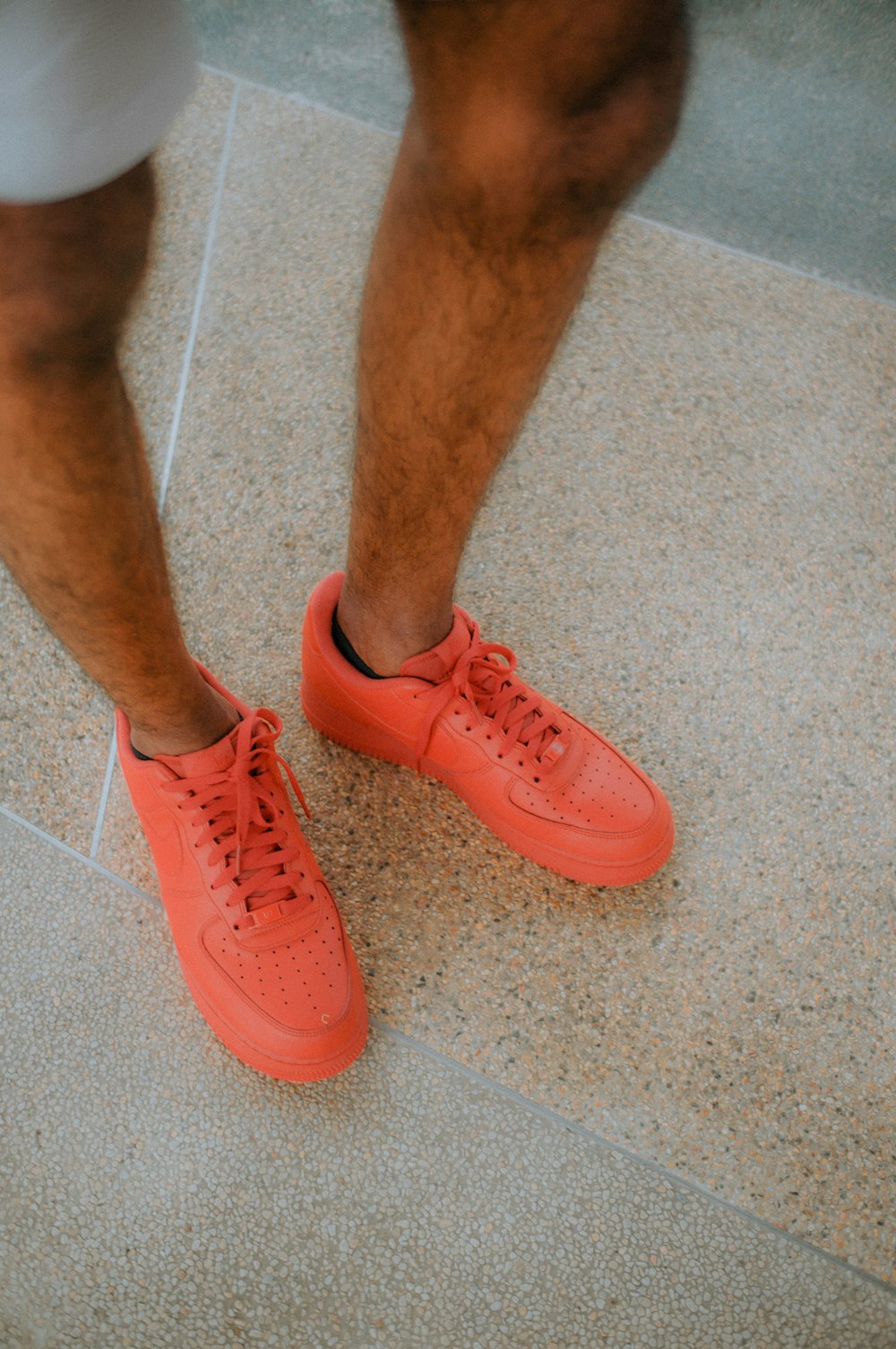 a person standing on a tile floor wearing orange sneakers