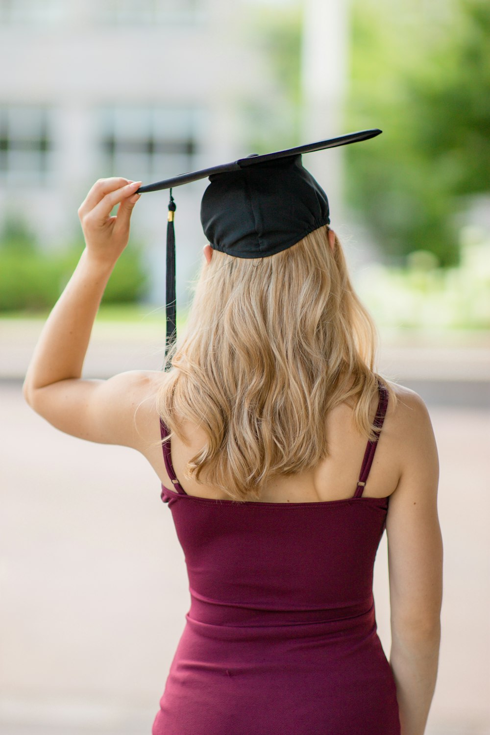 woman in red spaghetti strap top holding black mortar board during daytime