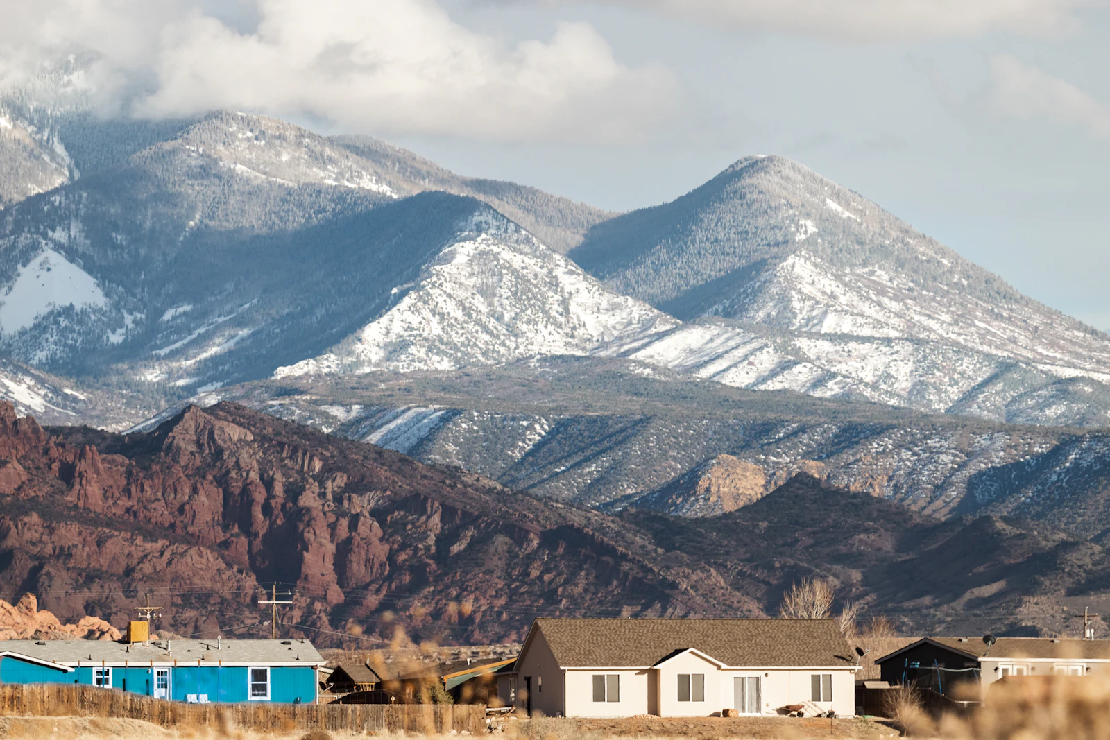 A modern white and brown concrete home built into a hillside, mountains in the background