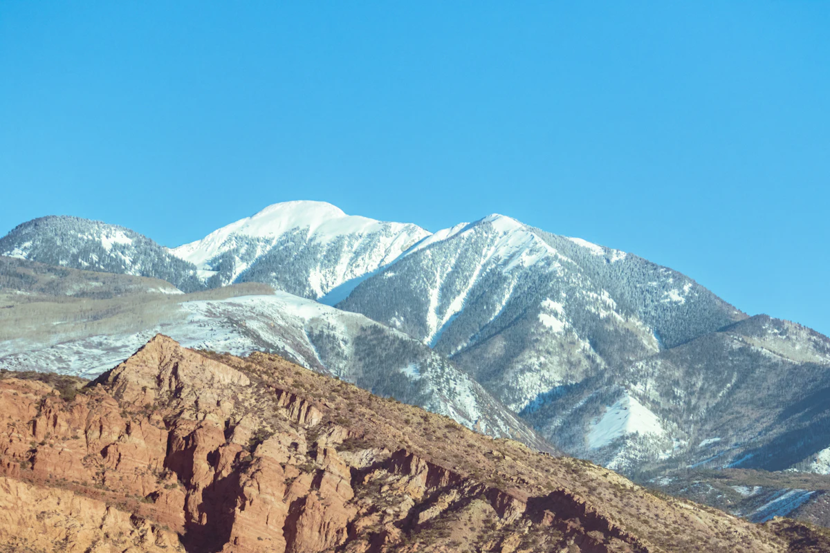 Snowy peaks of the La Sal Mountains above a red rock ridge