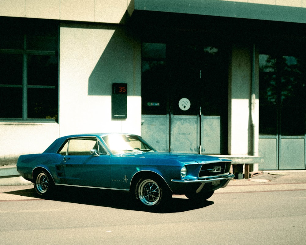 blue coupe parked beside white building