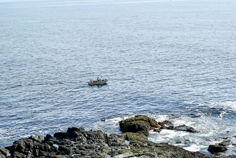 white boat on sea near rocks during daytime