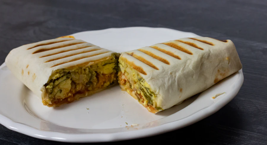 Breakfast wrap cut in half on a white plate
