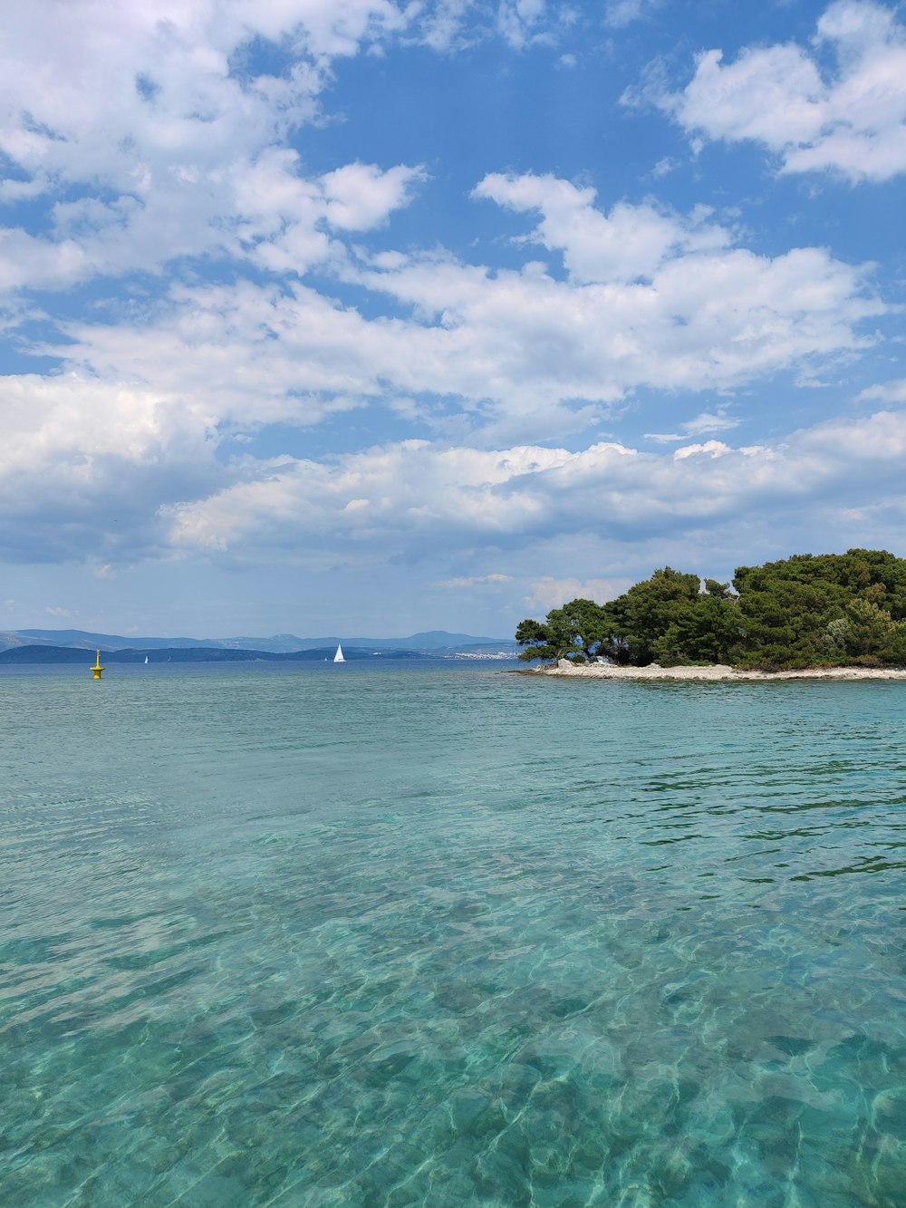 Grüne und braune Insel unter blauem Himmel und weißen Wolken tagsüber